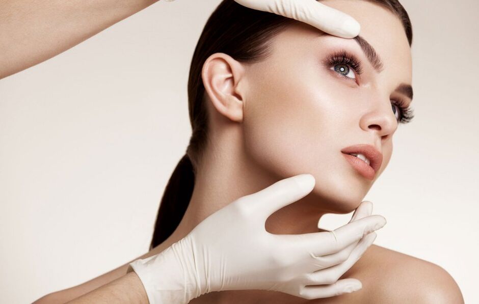 Kosmetikerin untersucht die Gesichtshaut vor der Verjüngung